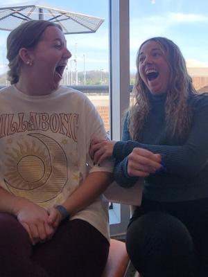 Two college students look at eachother and laugh at their caricature