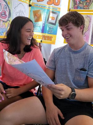 A couple admires their caricature at the market